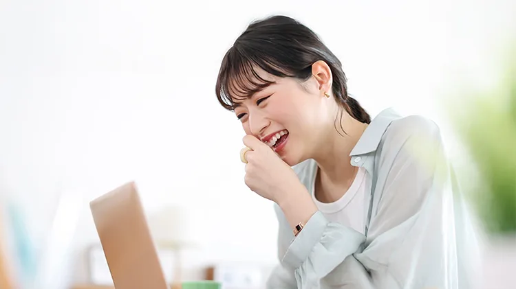 部屋で笑いながらオンラインで話す学生